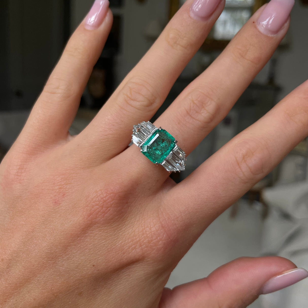 Vintage emerald and diamond engagement ring, worn on hand.