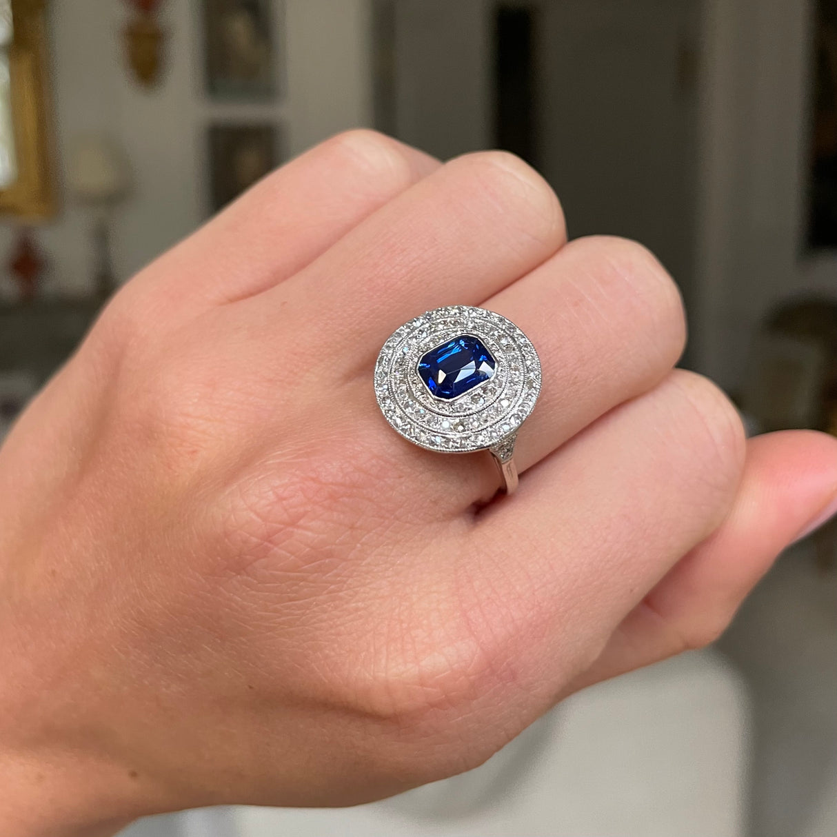 Sapphire and diamond target cluster ring, worn on closed hand. 