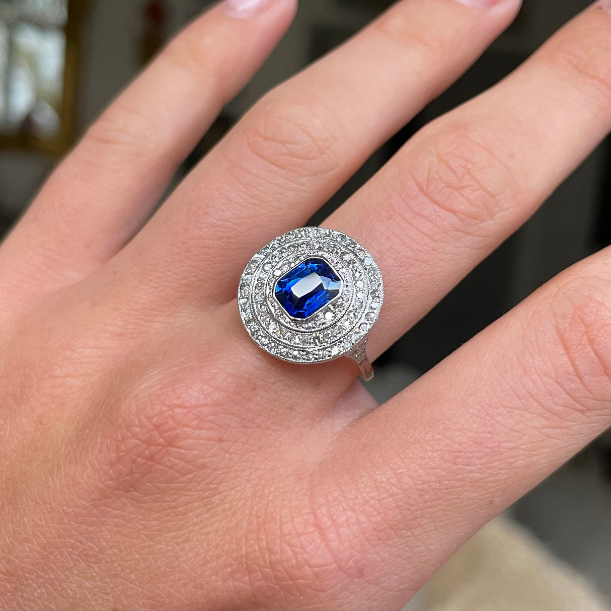 Sapphire and diamond target cluster ring, worn on hand.