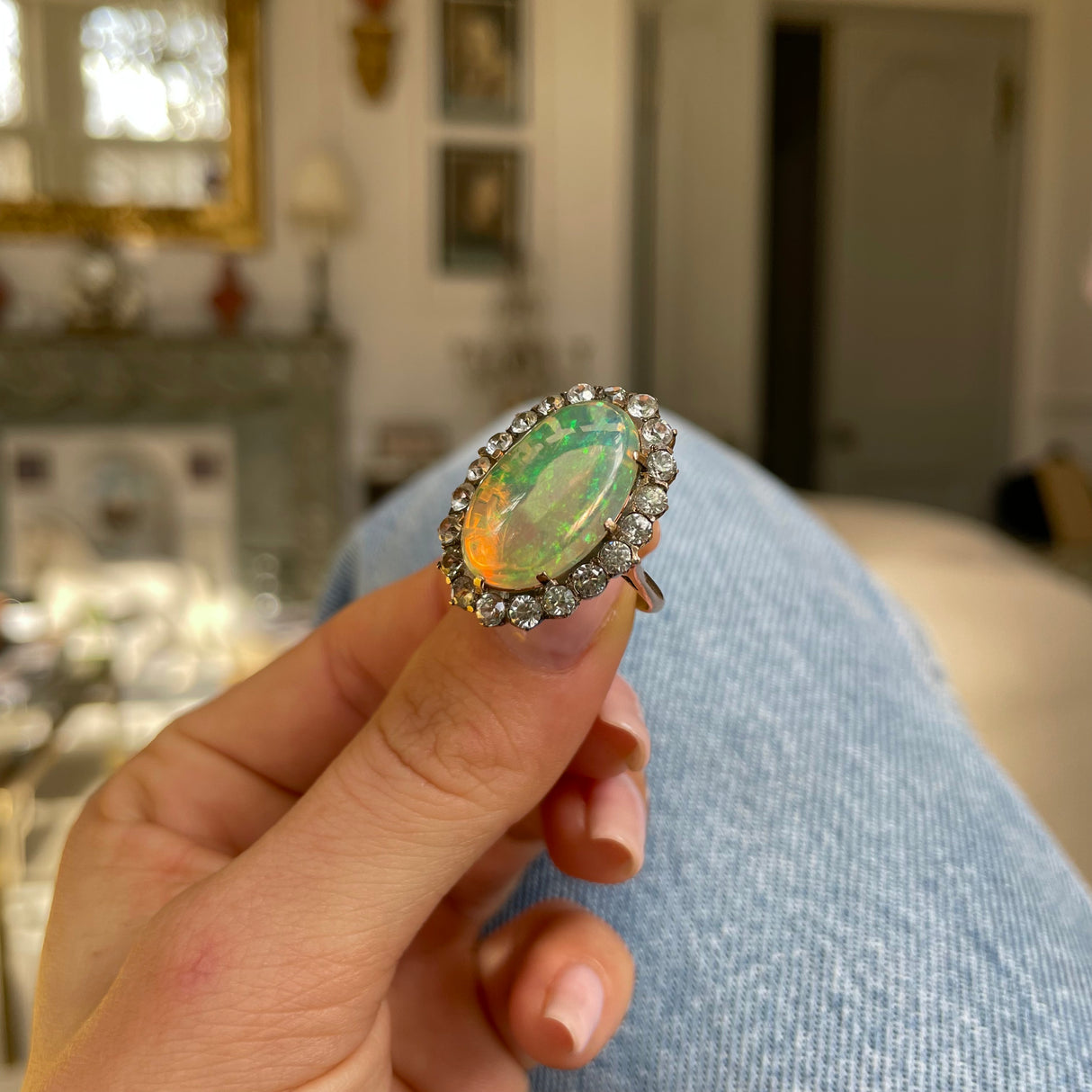 Antique opal and paste cluster ring, held in fingers.