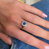 Sapphire and diamond engagement ring, worn on hand.