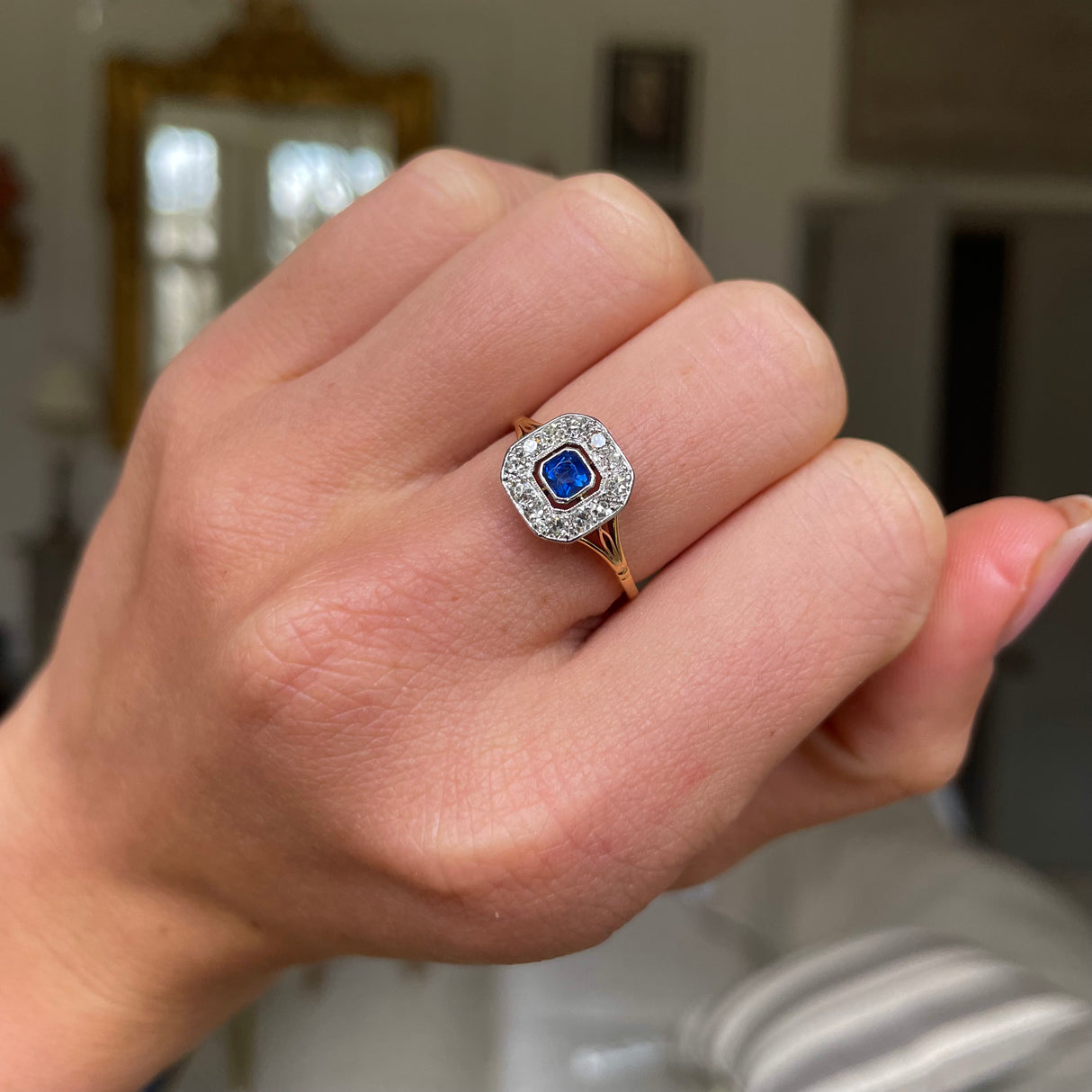 Sapphire and diamond engagement ring, worn on hand.