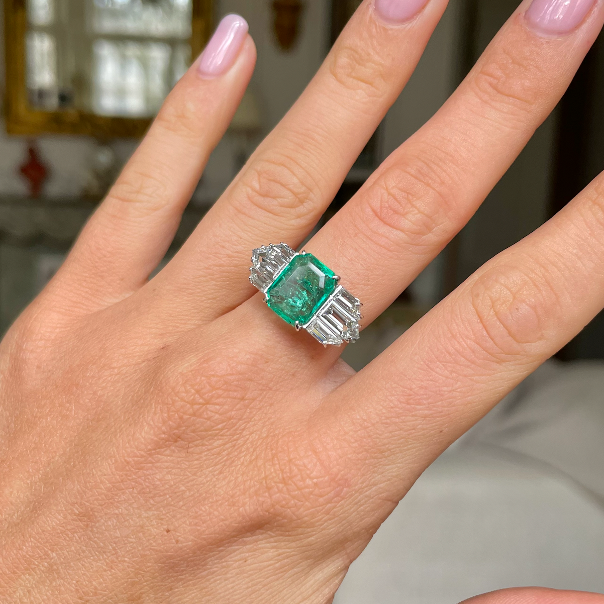 Vintage emerald and diamond engagement ring, worn on hand.