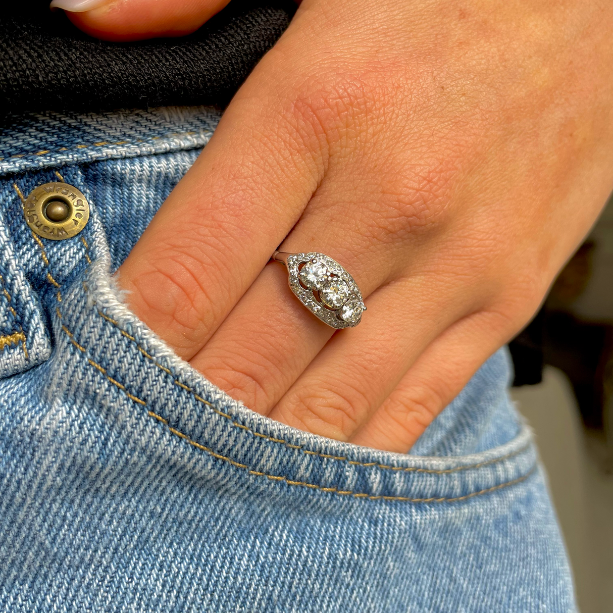Art Deco three-stone diamond engagement ring, worn on hand.