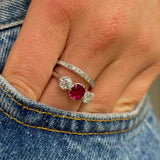 Ruby and diamond three-stone engagement ring, worn on hand.