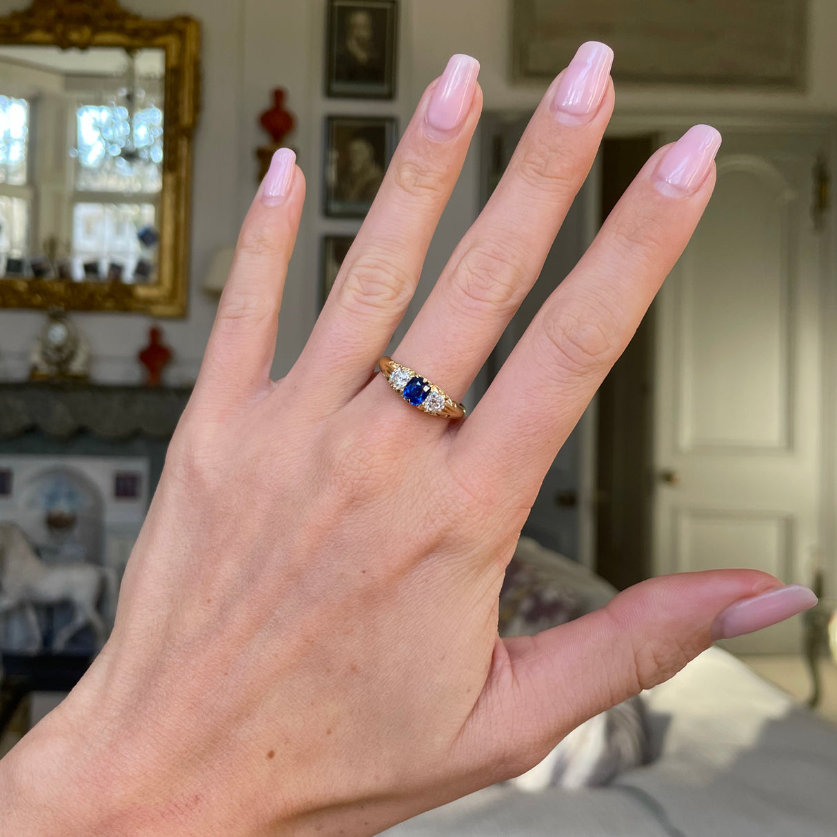 Sapphire and diamond three stone ring, worn on hand.