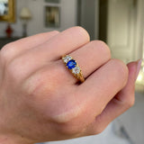 Sapphire and diamond three stone ring, worn on hand.