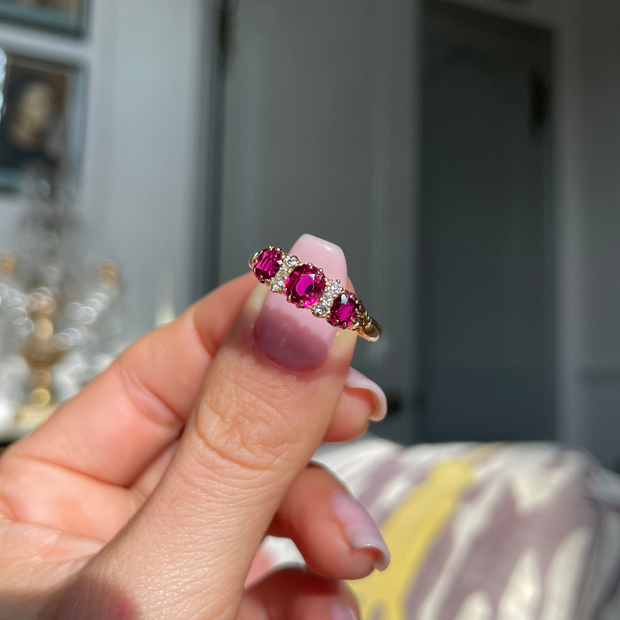 Victorian three-stone ruby and diamond engagement ring, held in fingers.