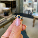 sapphire and diamond engagement ring, held in fingers.