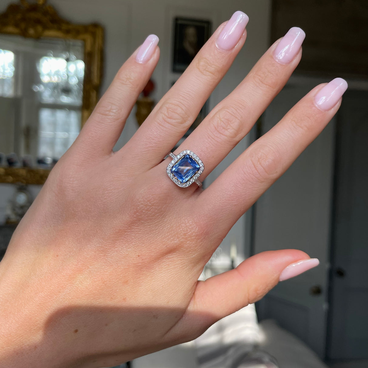 vintage sapphire and diamond cluster engagement ring worn on hand. 