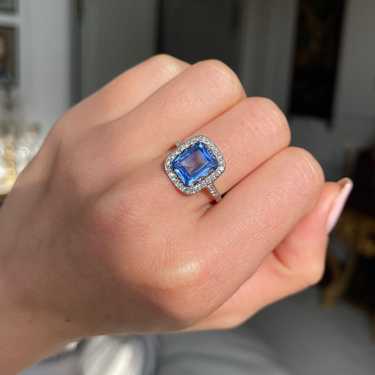 vintage sapphire and diamond cluster engagement ring worn on closed hand. 