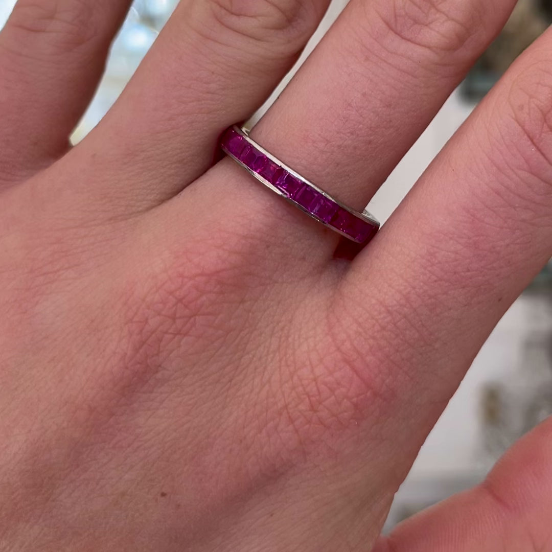 Pink sapphire eternity ring, worn on hand and moved away from camera to give perspective.
