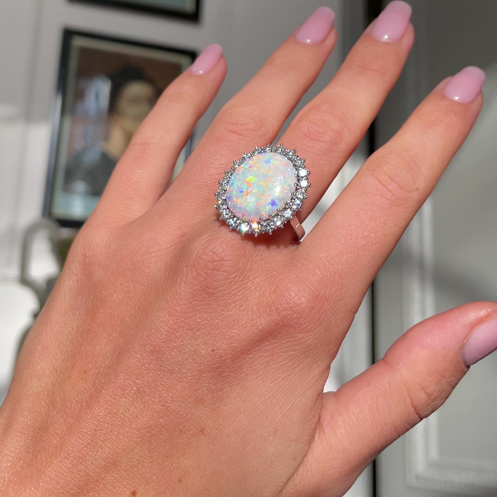 White opal and diamond cluster ring, worn on hand and rotated to give perspective.