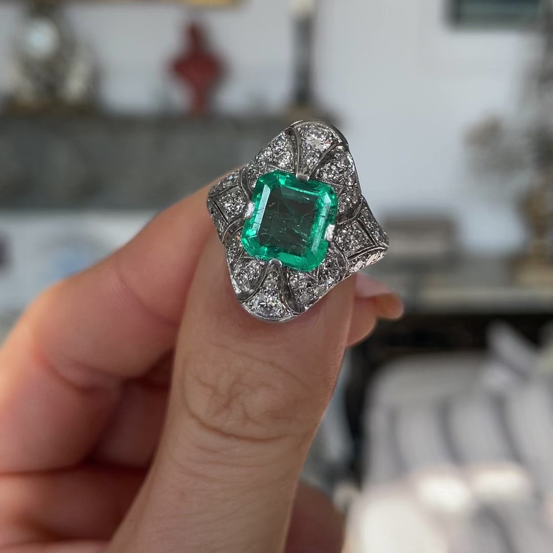 Art Deco emerald and diamond ring, held in fingers and moved around to give perspective.